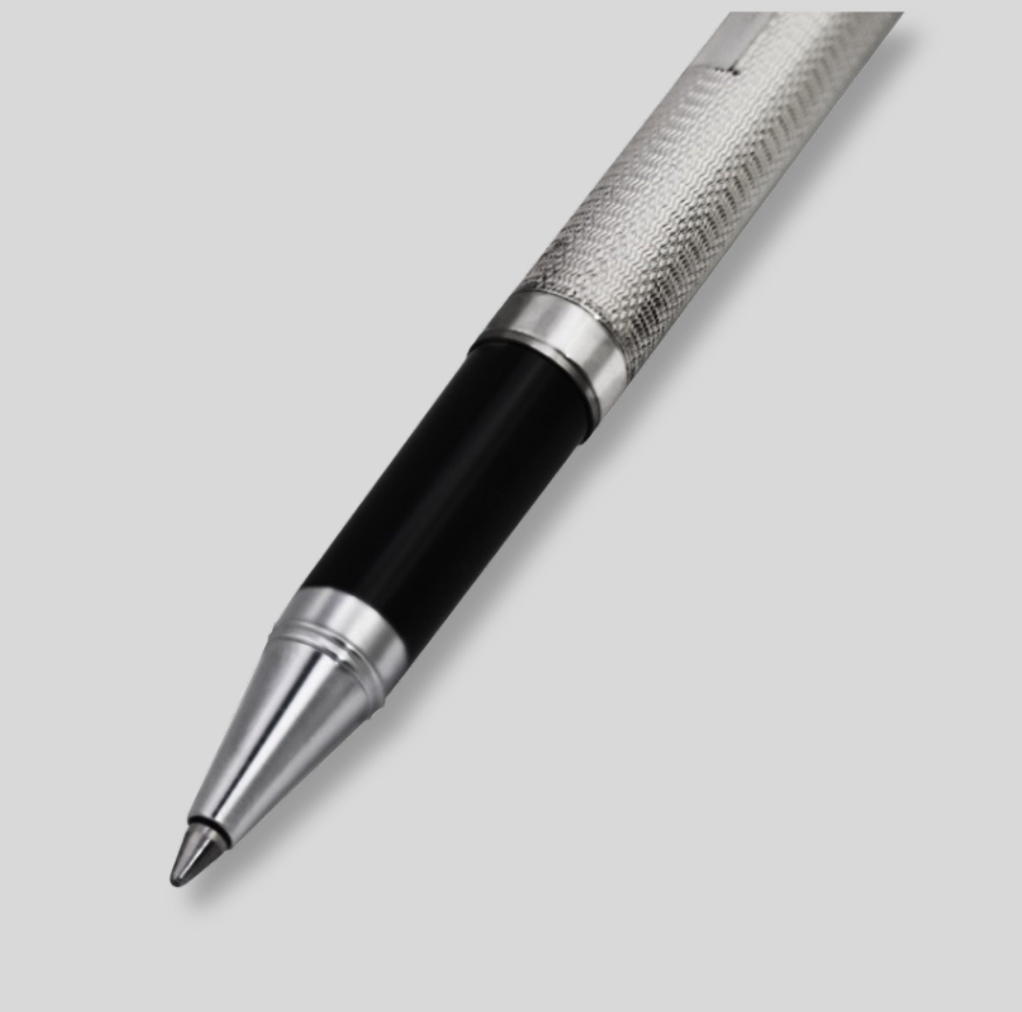 A luxury ballpoint pen with a textured silver metal grip, a glossy black barrel, and polished silver accents, shown diagonally on a light gray background.