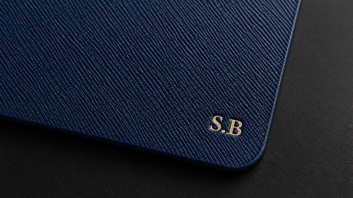Close-up of a navy leather Leathersmith notebook with gold embossed “S.B” initials in the bottom right corner.